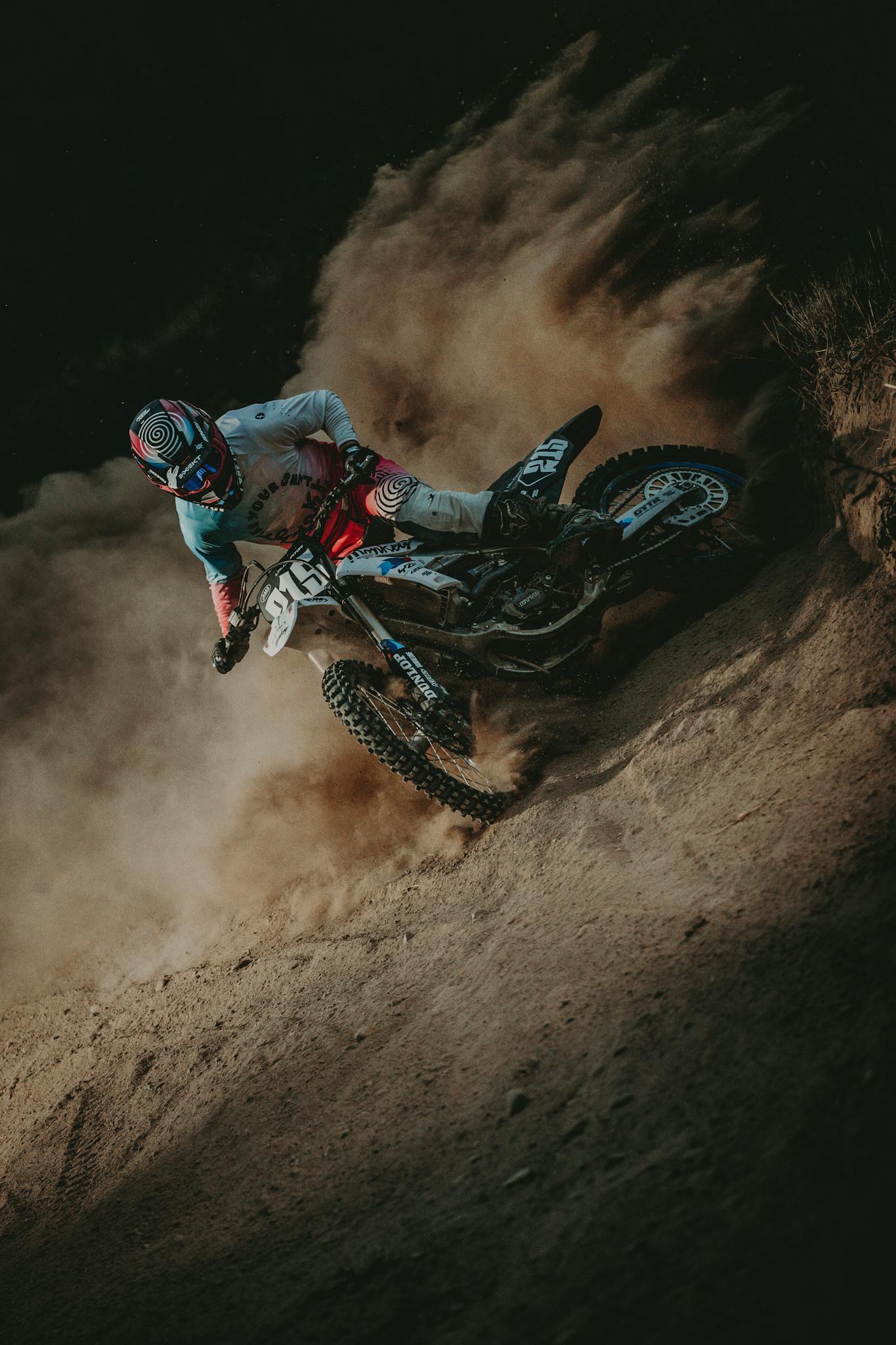 Thrilling motocross action as a racer accelerates on a dusty trail during the day.