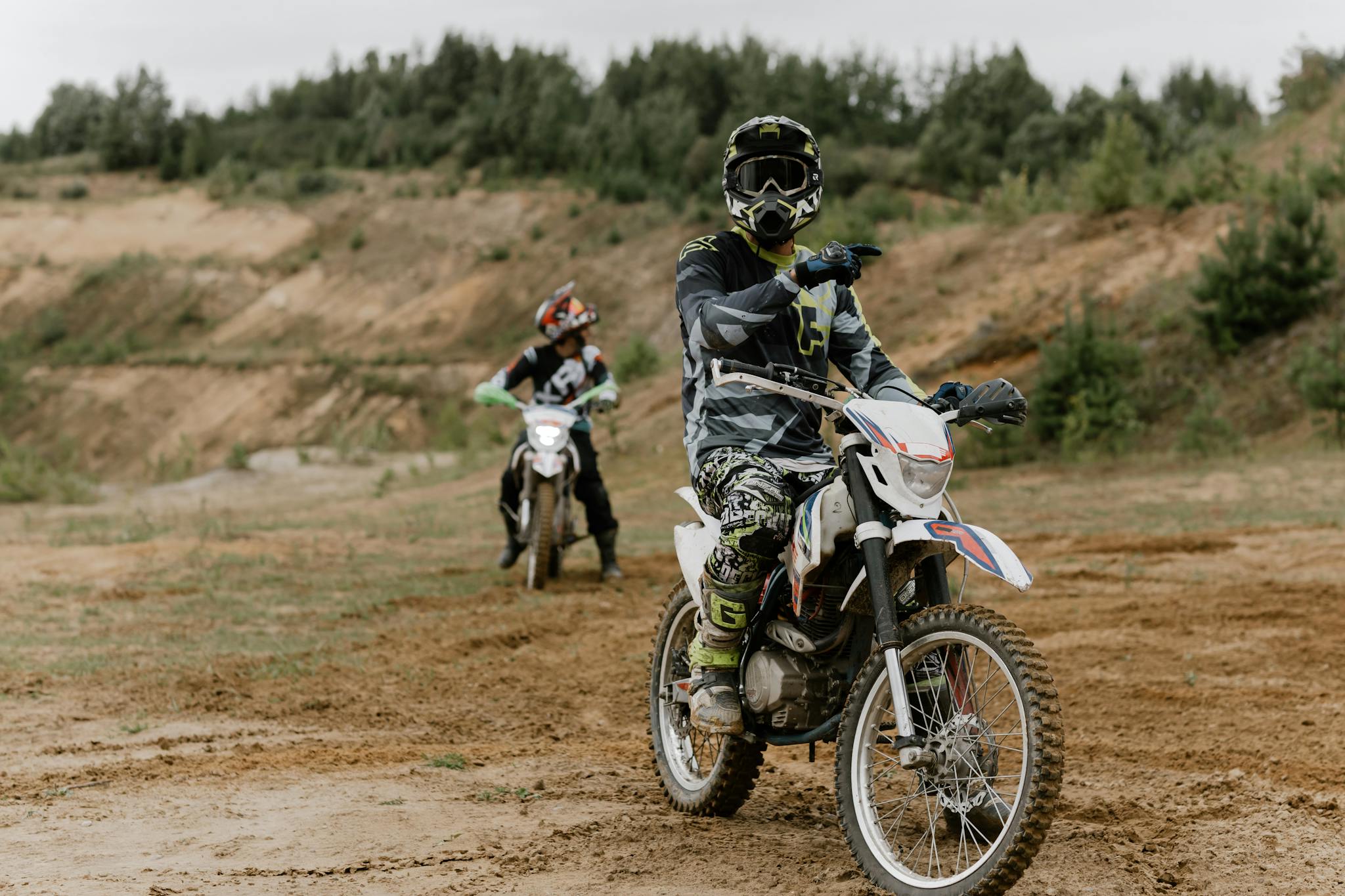 Two riders on dirt bikes navigate an off-road trail for an adventurous motocross experience.